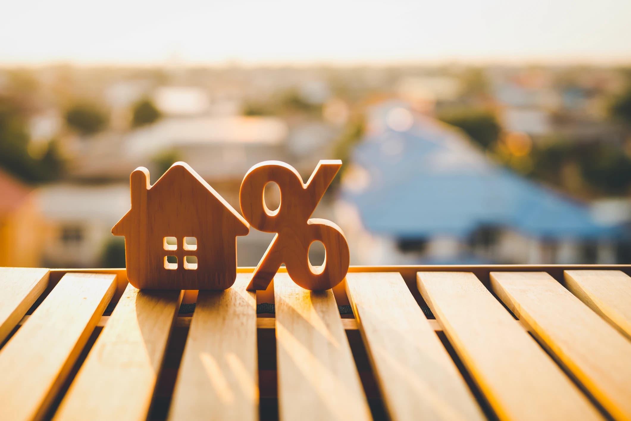 Wooden house and percentage symbols overlooking a suburban neighbourhood