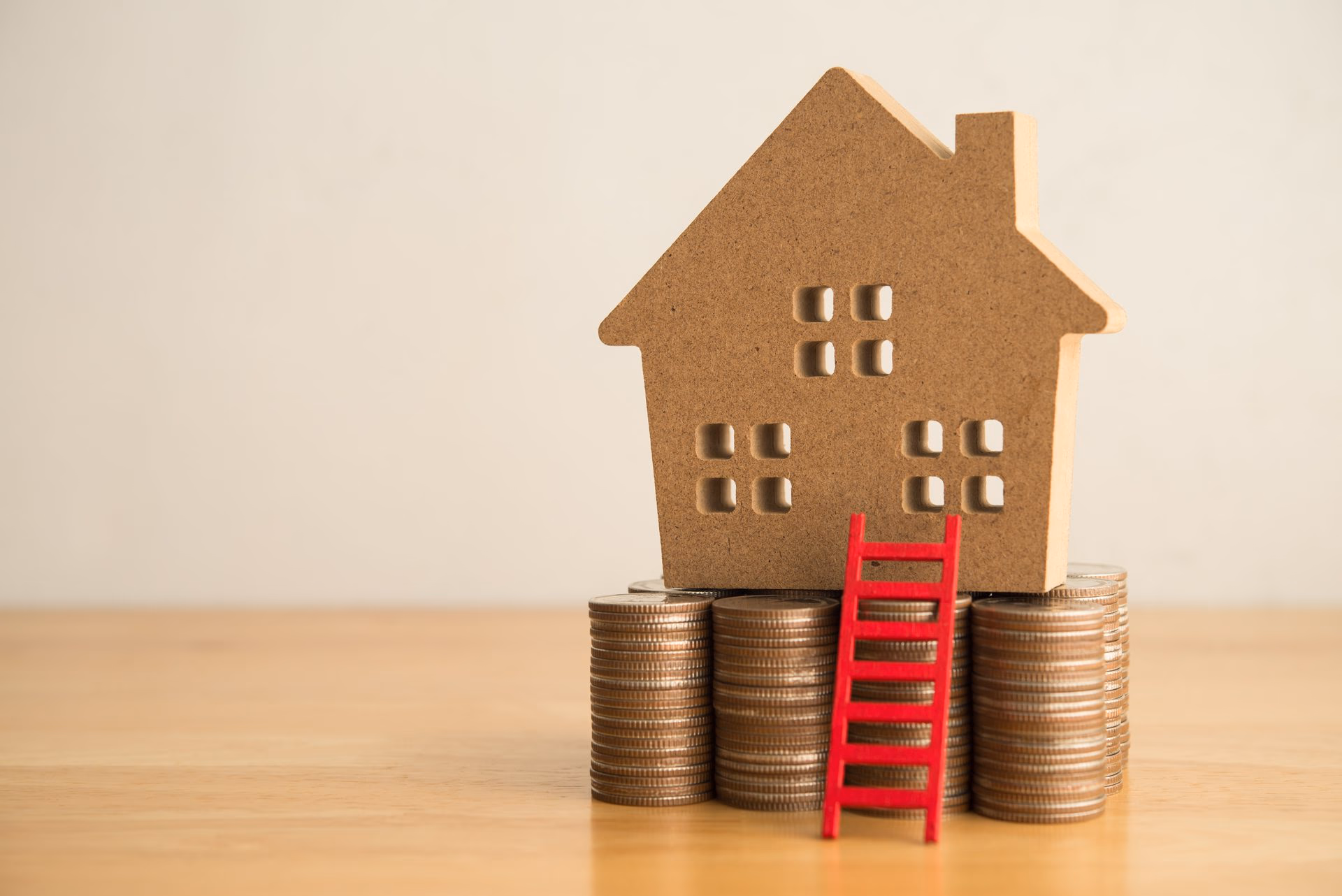 Model house on coin stacks with red ladder