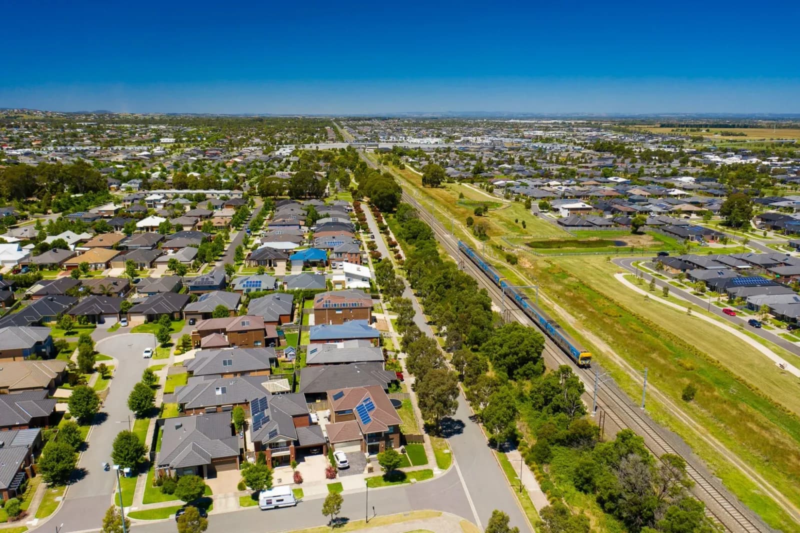 Aerial view of suburban homes beside a major road and rail corridor