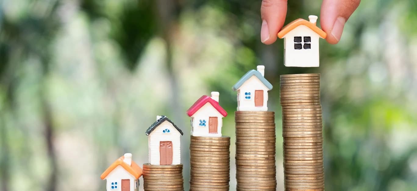 Miniature houses on stacks of coins