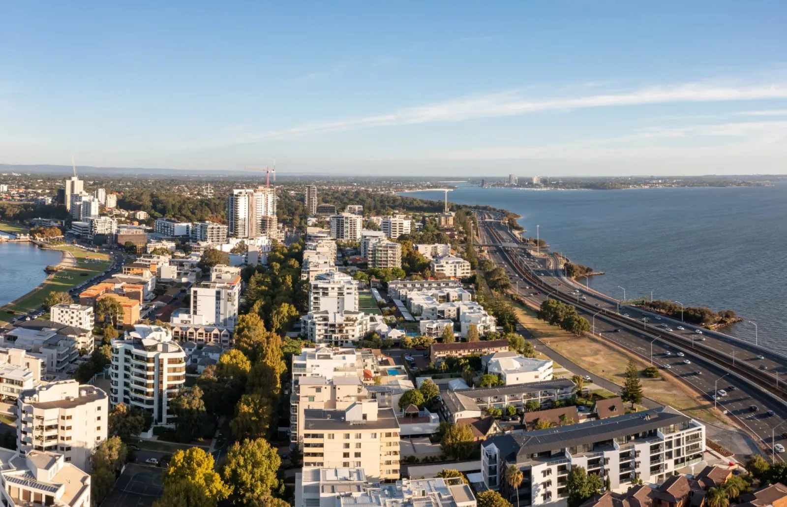 Aerial perspective of buildings and a highway by the water.