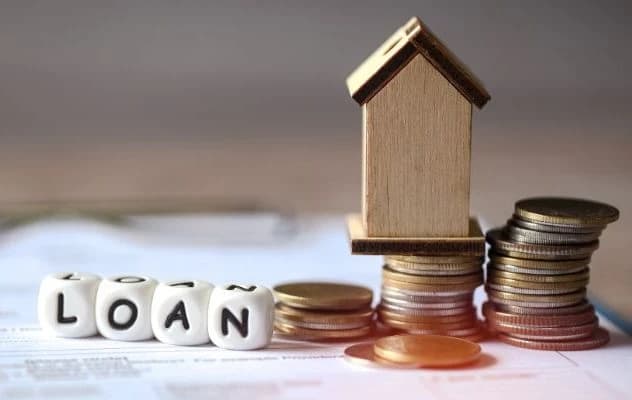 Loan dice, miniature house, and stacks of coins.