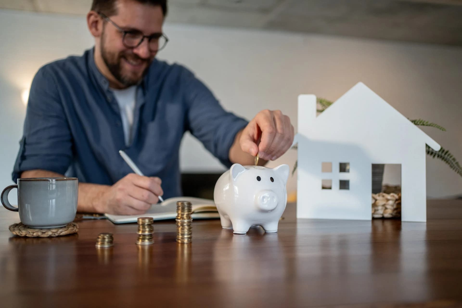 Man saving money in piggy bank near house model