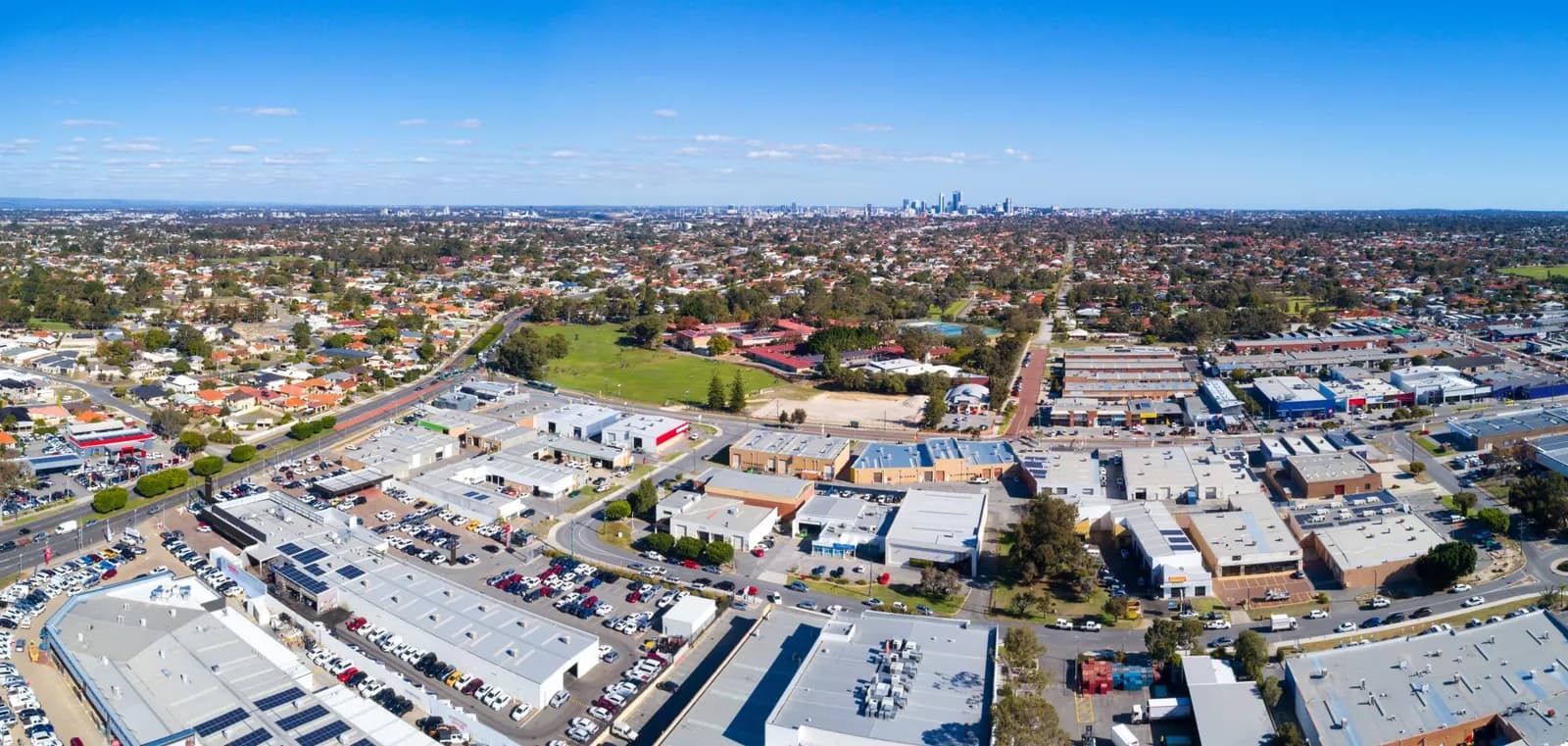 Aerial view of industrial and residential areas with distant city skyline.