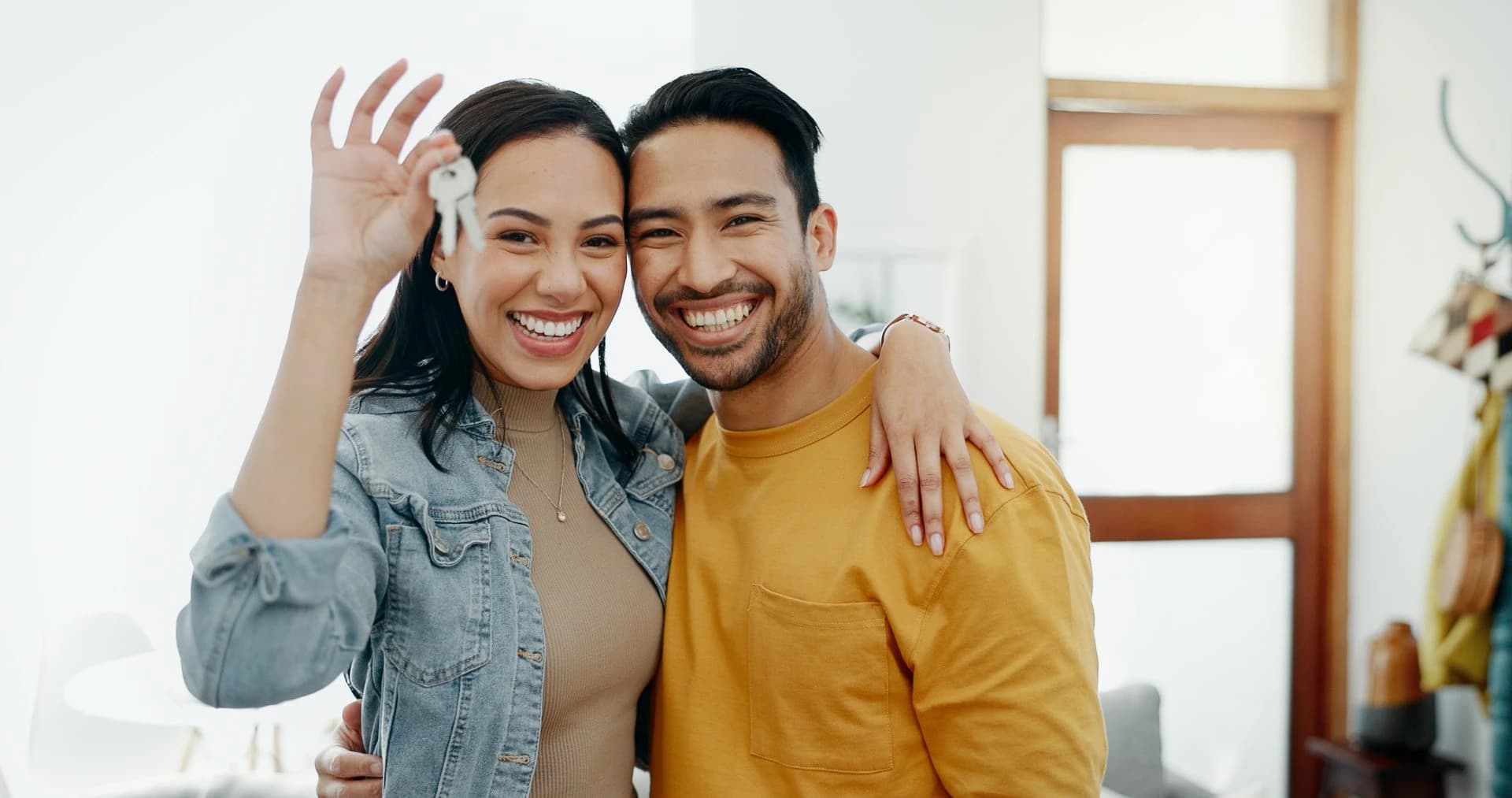 Smiling couple holding house keys inside their new home