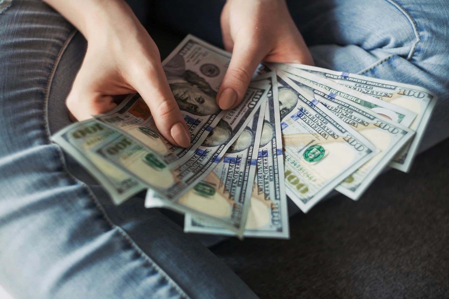 Fanned out US $100 bills held by hands