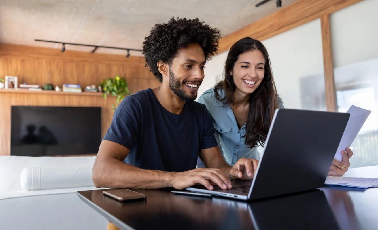 Couple smiling working on laptop