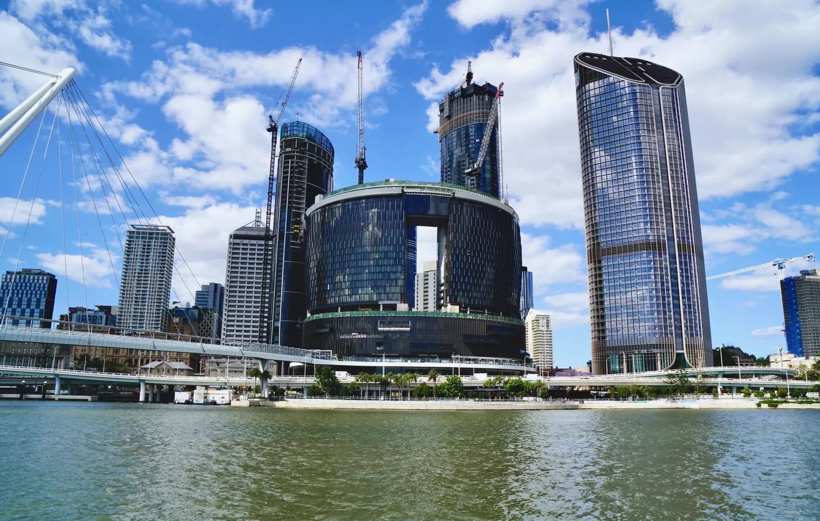 Modern high-rise buildings under construction and a bridge.